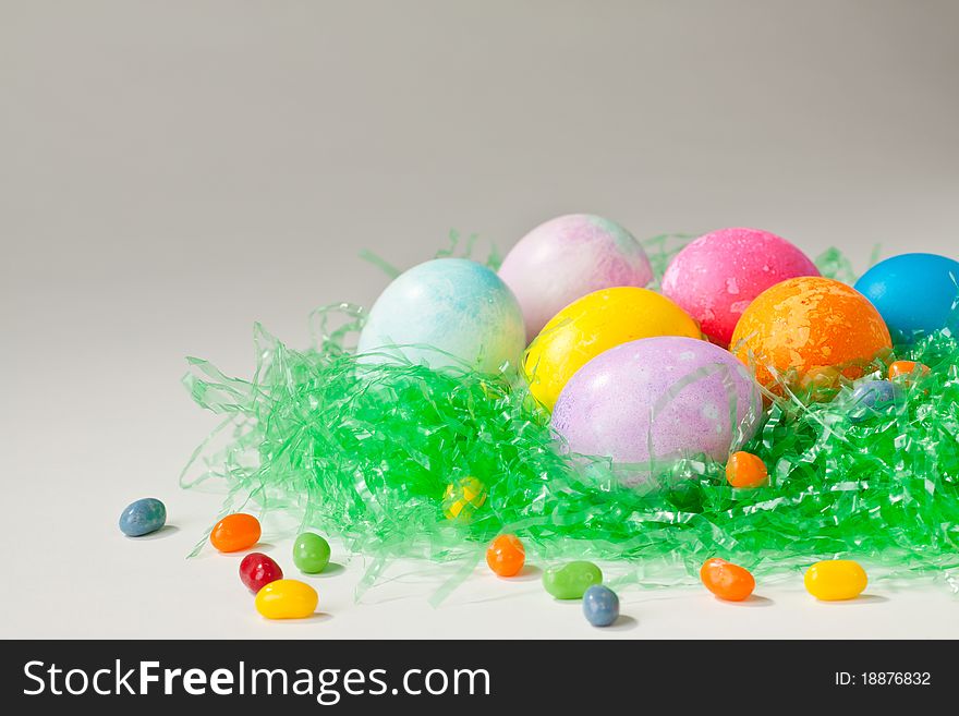 Brightly decorated easter eggs and jelly beans in green nesting material