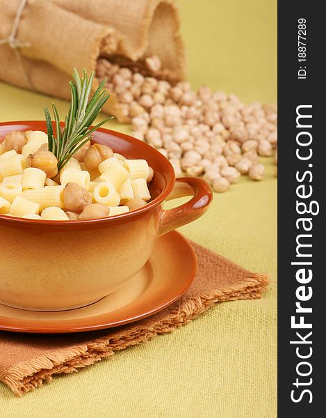 Small thimbles (ditalini) with chickpea and rosemary served in a ceramic bowl. Chickpeas spilling out from a jute bag in the background. Shallow DOF. Small thimbles (ditalini) with chickpea and rosemary served in a ceramic bowl. Chickpeas spilling out from a jute bag in the background. Shallow DOF