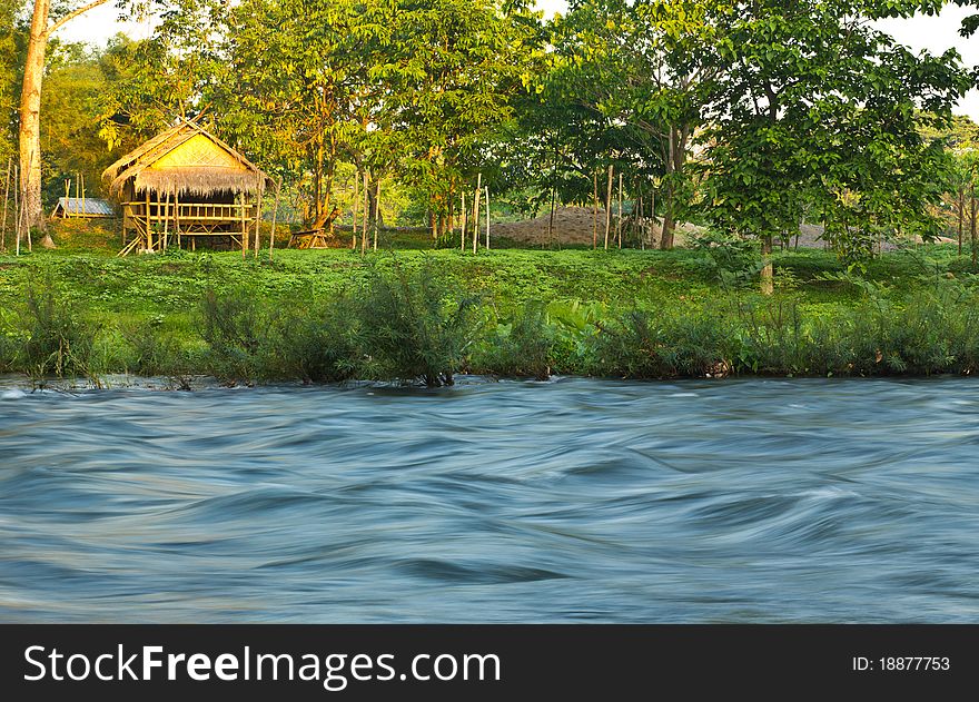 Landscape of the flowing swiftly river and hut