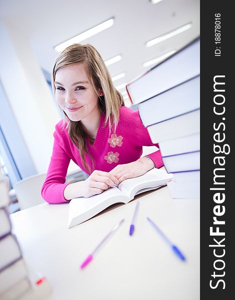 In the library - pretty, female student with laptop and books working in a high school library (color toned image)