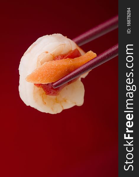 Shrimp from an appetizer in red chopsticks on a red background. Shrimp from an appetizer in red chopsticks on a red background.