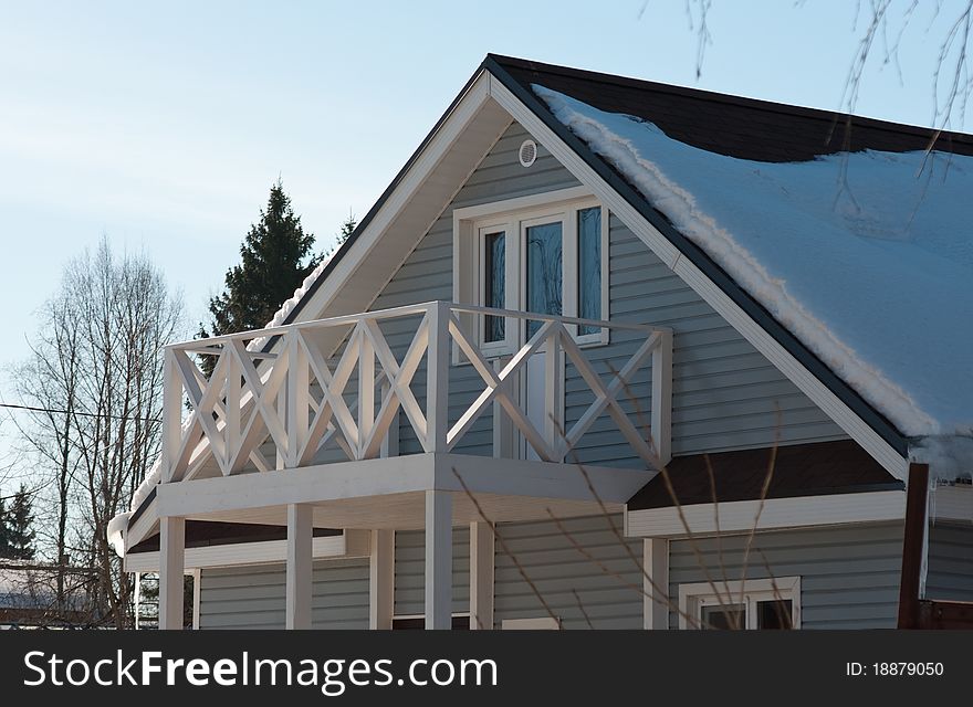 Balcony with openwork railing under the roof of the cottage