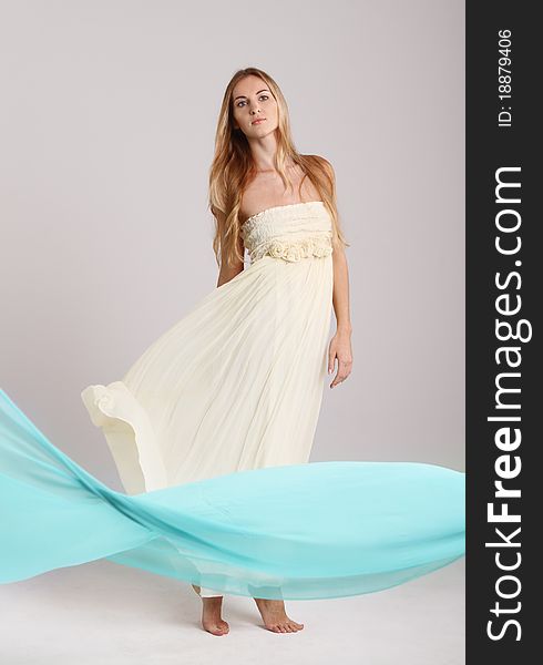 Young fashionable blond girl in long dress. Studio