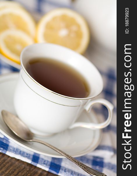 Cup of tea with lemon on blue-white napkin