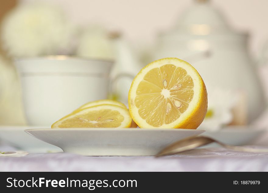 Teapot on table with lemon on foreground. Toned image. Teapot on table with lemon on foreground. Toned image