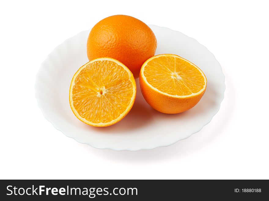 Two oranges on the white plate. One orange is sliced.