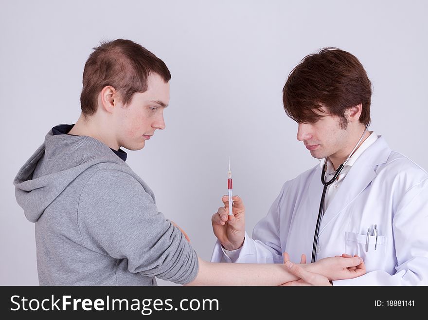 A young man gets an injection from a doctor. A young man gets an injection from a doctor