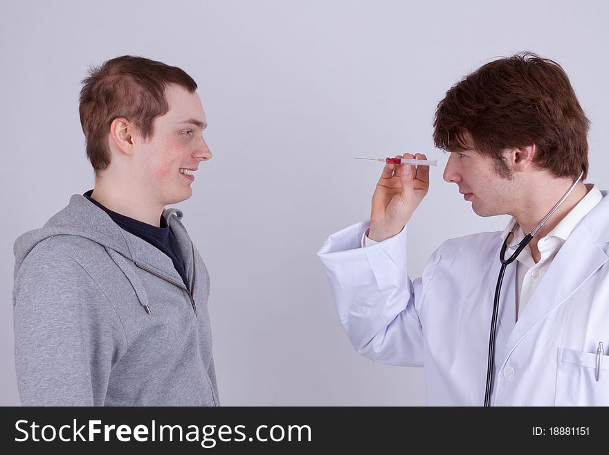 A young man gets an injection from a doctor. A young man gets an injection from a doctor