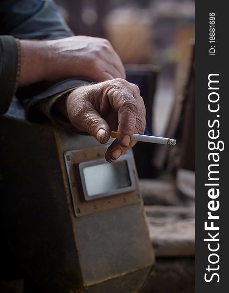 Hand working with a cigarette and a protective helmet. Hand working with a cigarette and a protective helmet