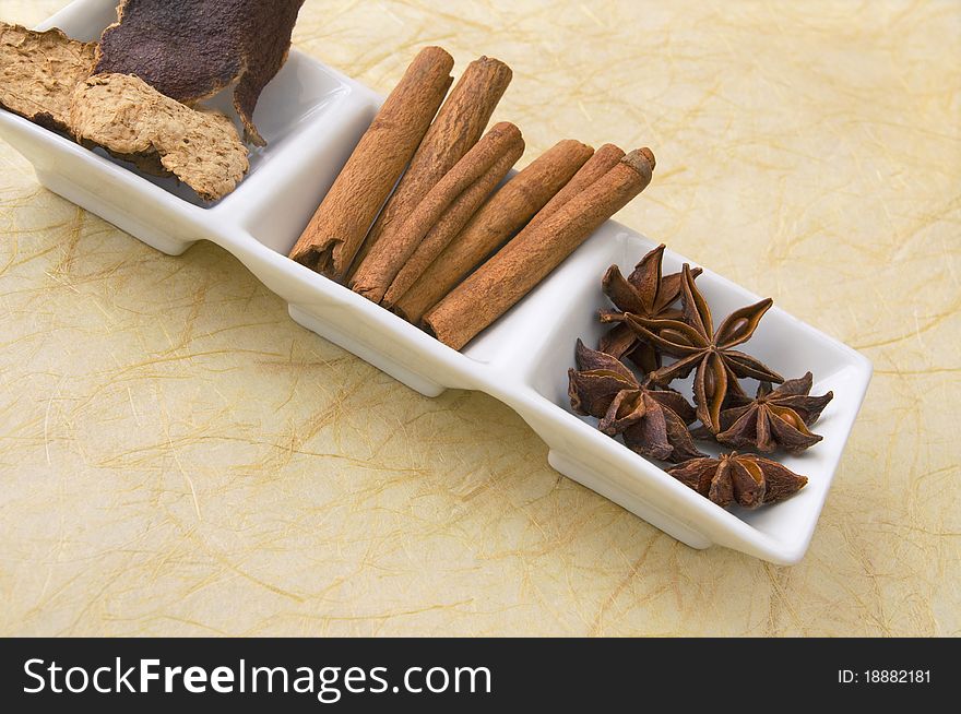 Dried star anise, cinnamon sticks and tangerine peel - herbs and spices in white ceramic dish. Dried star anise, cinnamon sticks and tangerine peel - herbs and spices in white ceramic dish.