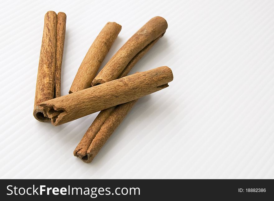 Dried cinnamon sticks on a white linear textured tabletop. Dried cinnamon sticks on a white linear textured tabletop.