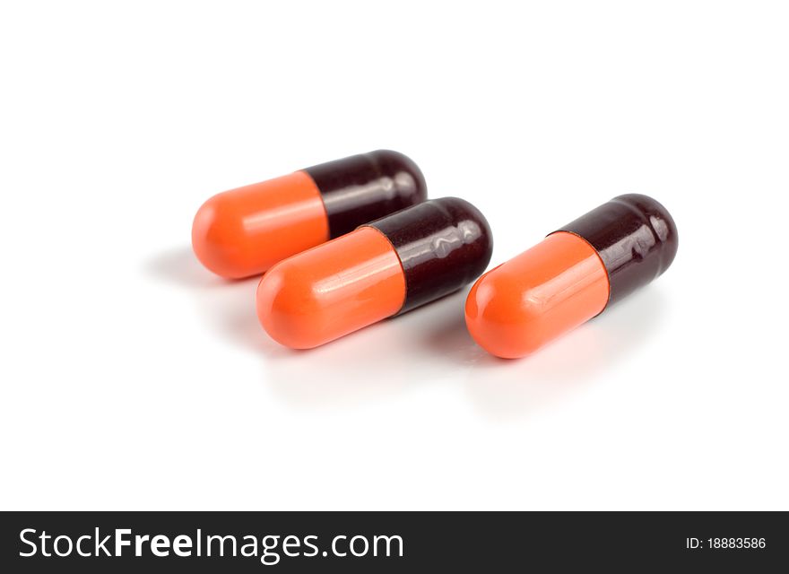 A orange/black capsuled isolated on a white background. A orange/black capsuled isolated on a white background