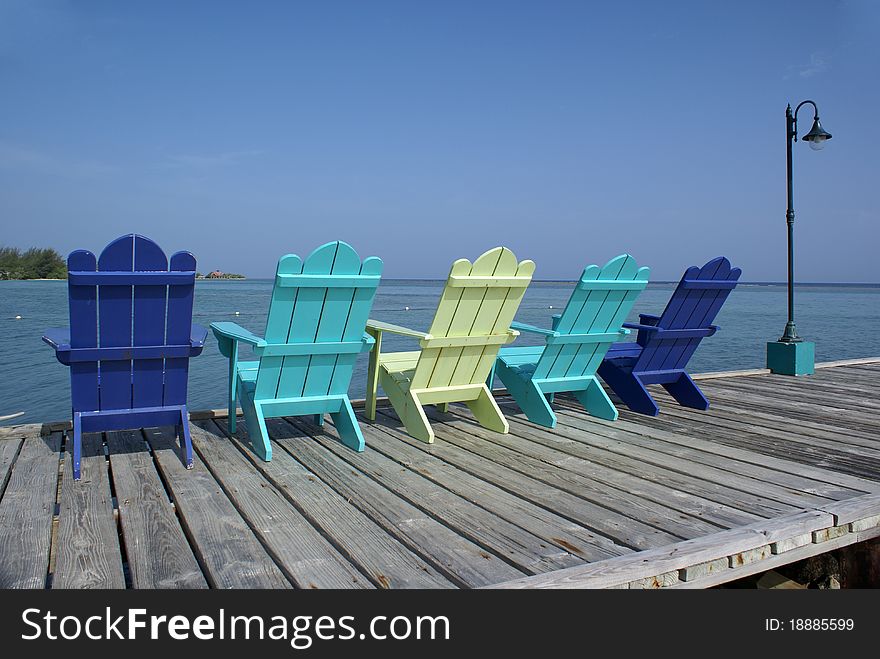 Colorful Adirondack chairs lined up on the pier. Colorful Adirondack chairs lined up on the pier