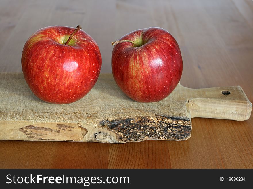 Two apples on wooden chopping board