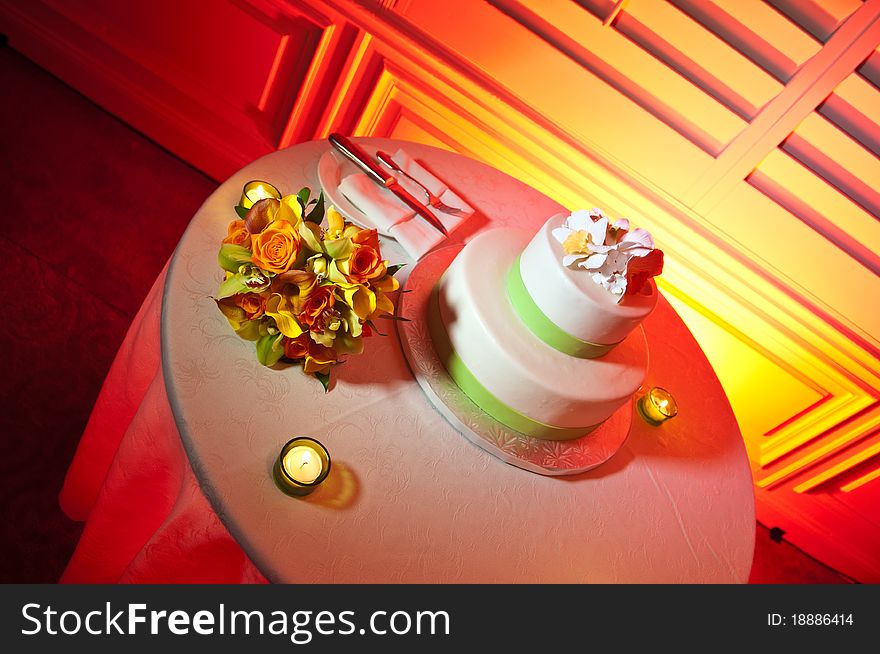 Green and White wedding cake on Red Table surrounded by candles and bride's bouquet