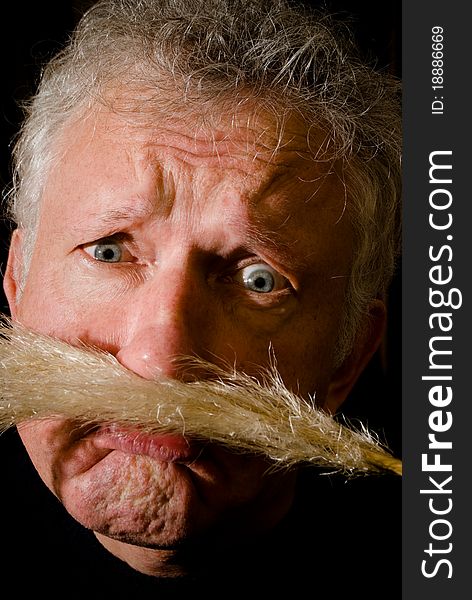 Portrait of a worried man with reed between lip and nose