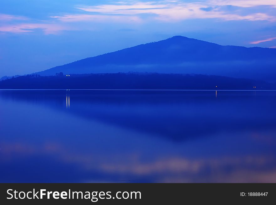 Reflection of a mountain and village lights on a lake, at night. Reflection of a mountain and village lights on a lake, at night