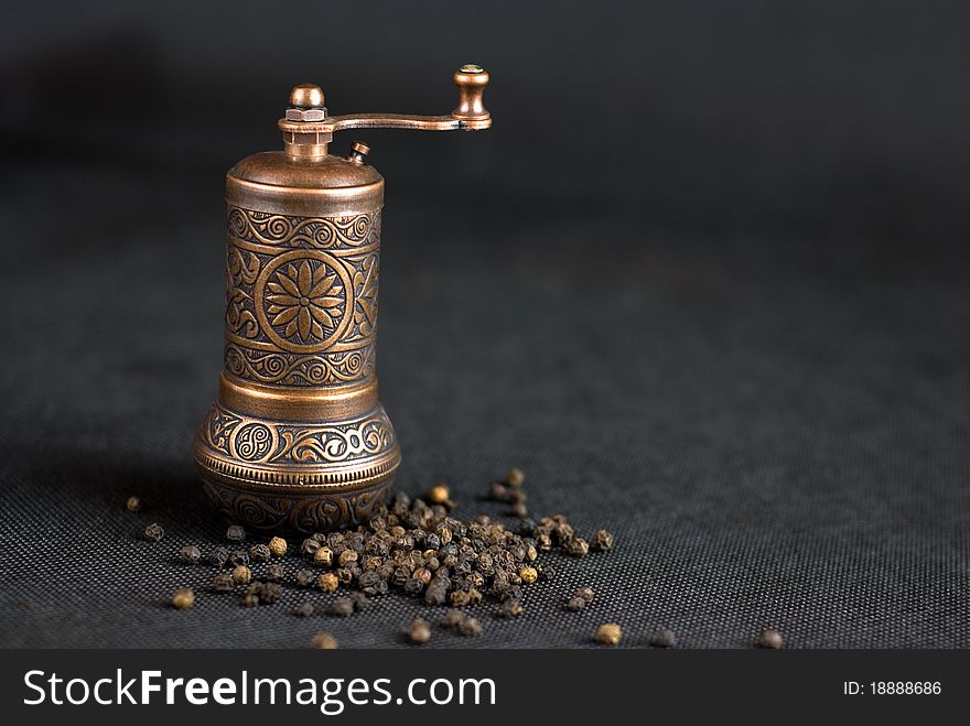 Vintage still life with brass pepper mil standing on the grey background