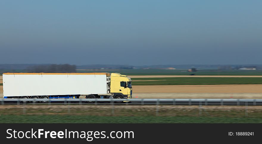 Panning image of a big white track on a highway in a plain area. Panning image of a big white track on a highway in a plain area.