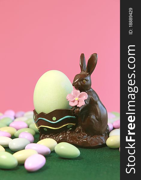 Chocolate Easter bunny holding egg with pastel candy