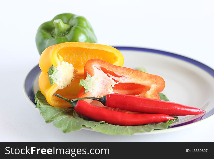 Hot and spicy salad containing red chillies and green, yellow and red capsicum on white background