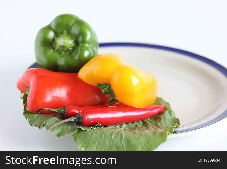 Hot and spicy salad containing red chillies and green, yellow and red capsicum on white background