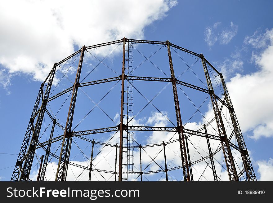 A gasometer against a blue sky with clouds