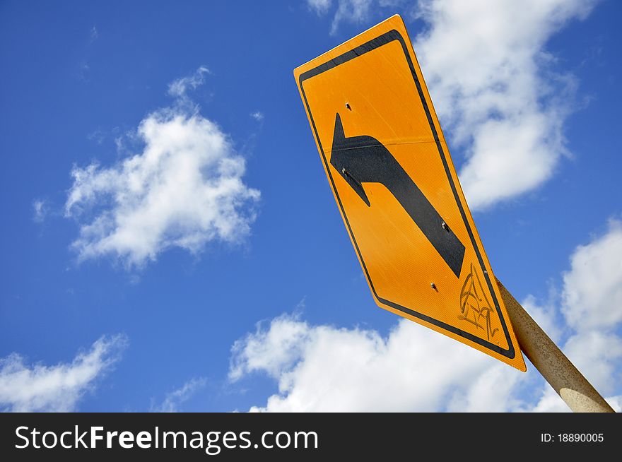 Curved Road Traffic Sign under the blue sky with clouds