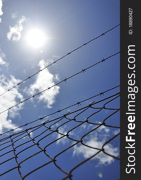 Fence with barbed wire under blue sky