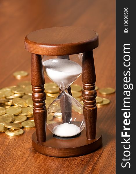 Hourglasses and coin On a wooden table