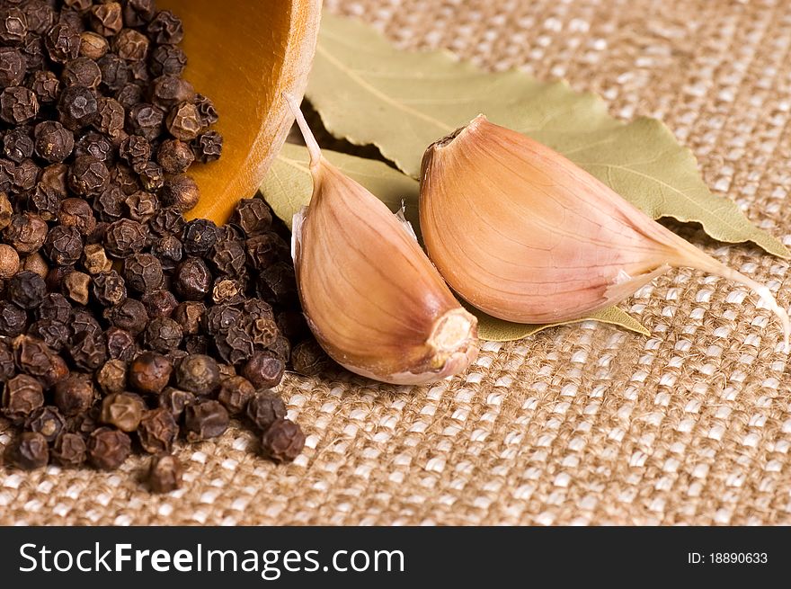 Black Peppercorns with garlic and a bay leaf still life