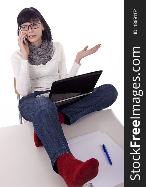 Brunette woman sits thrown feet on the desk and talking on the phone on white background. Brunette woman sits thrown feet on the desk and talking on the phone on white background