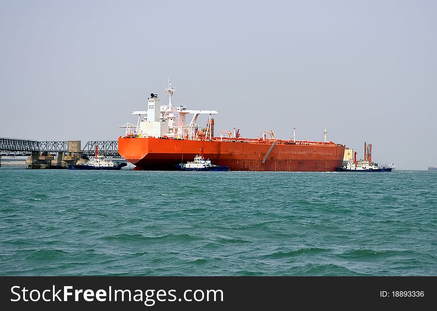 A huge oil tanker and tugboats at work. A huge oil tanker and tugboats at work