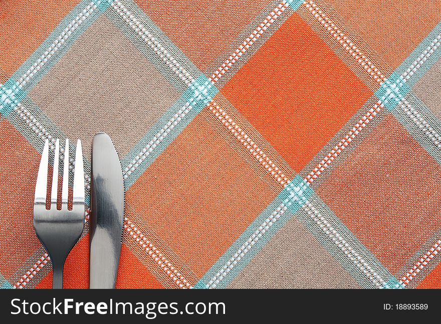 Fork and table knife lying on chequered tablecloth. Fork and table knife lying on chequered tablecloth