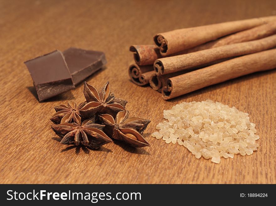 Cinnamon, anise, chocolate and brown sugar laying on wooden background