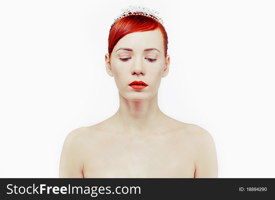 Closeup fashion portrait red-hair girl with tiara against white background. Model dropped her eyes. Closeup fashion portrait red-hair girl with tiara against white background. Model dropped her eyes