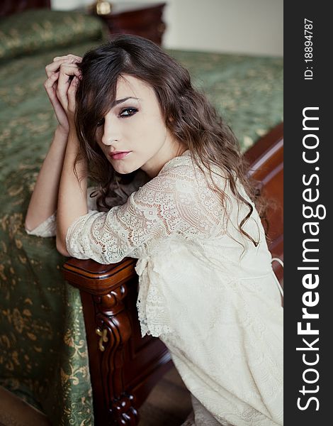 Portrait of a young woman sitting next to the bed of a hotel room