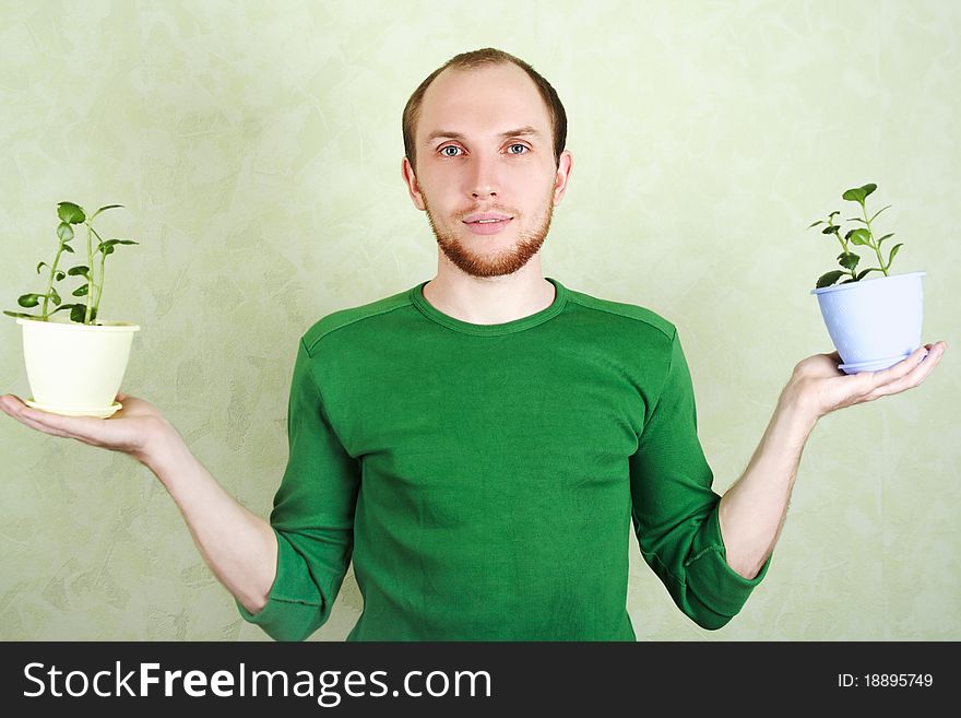Man in green shirt holding two flowerpots with Kalanchoe plants. Man in green shirt holding two flowerpots with Kalanchoe plants