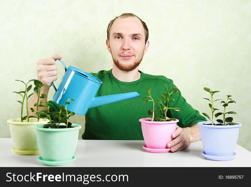 Man Sitting Near Table And Watering Plants