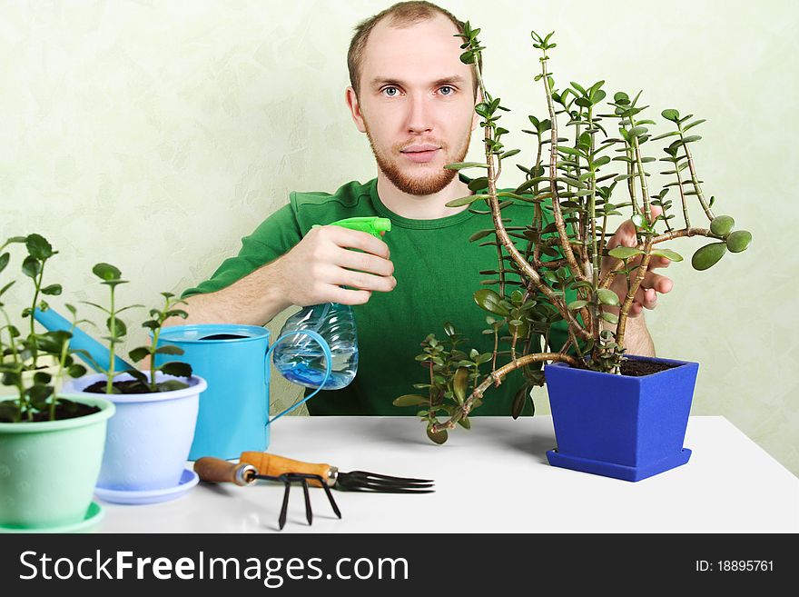 Man sitting near table with gardening equipment and pronging ground in flowerpot