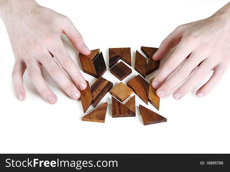 Closeup of mans hands assembling wooden square puzzle, isolated