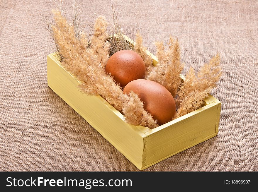 Two chicken eggs in a wooden box