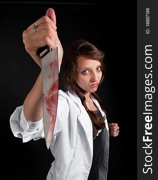 Mad nurse holds a bloody knife in the dark