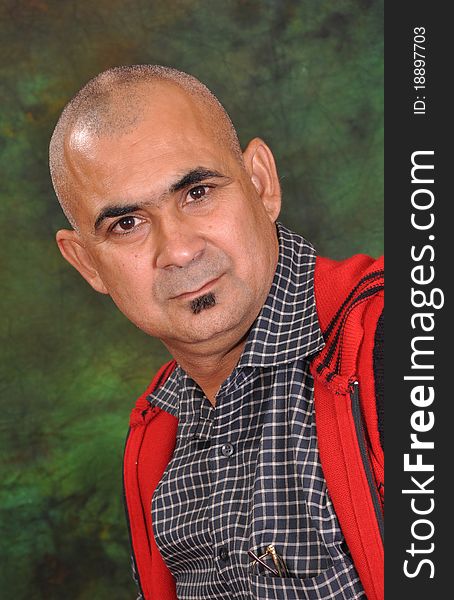 Good looking and handsome bald man standing before a green background. he is focusing the camera with his own eyes. Good looking and handsome bald man standing before a green background. he is focusing the camera with his own eyes.