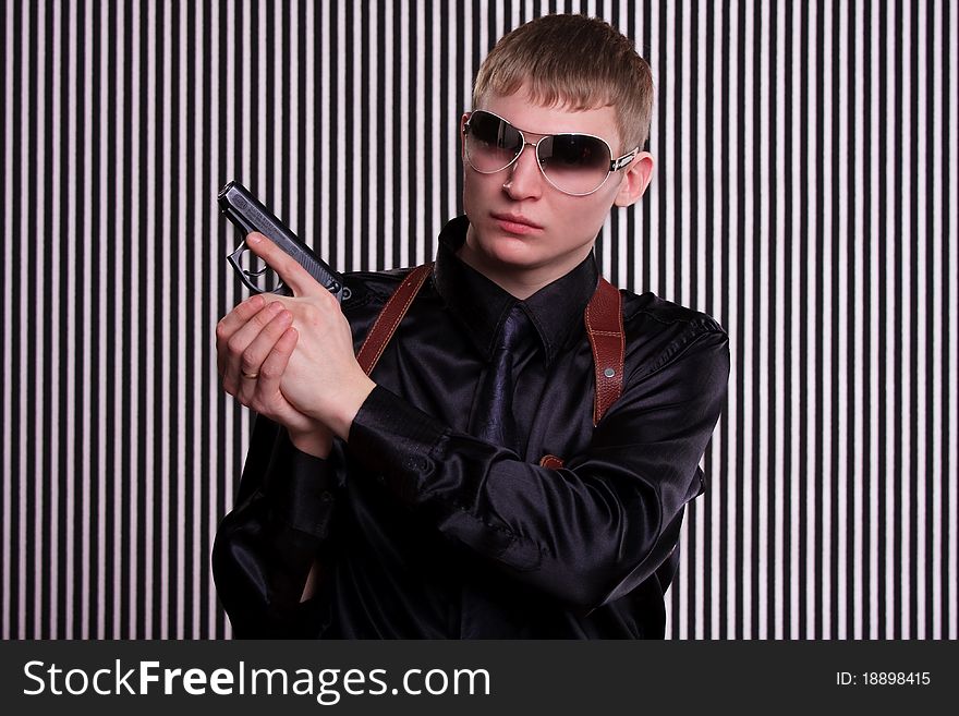 Serious man with a gun standing against striped background