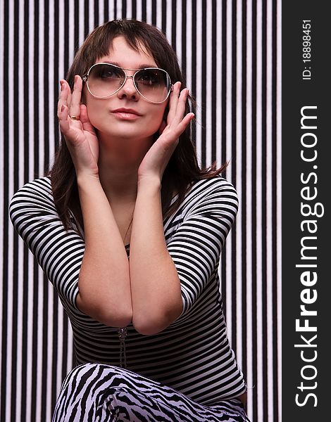 Cute girl in a striped clothes and sunglasses on the striped background