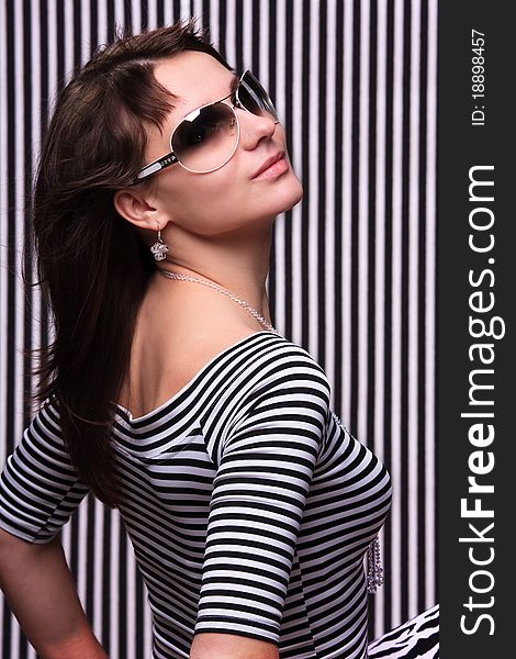 Cute girl in a striped clothes and sunglasses on the striped background