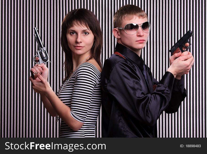Young couple holding guns over stripe background