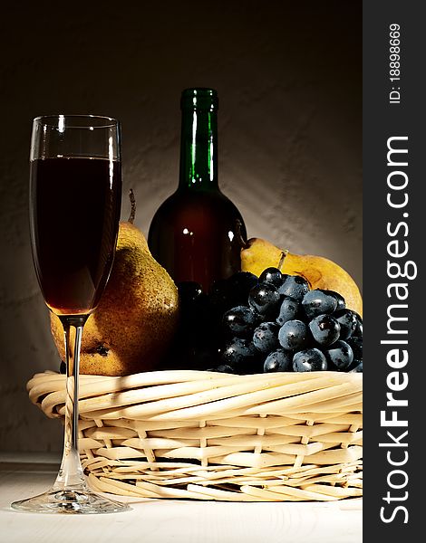 Still life with red wine and fruits on the desk