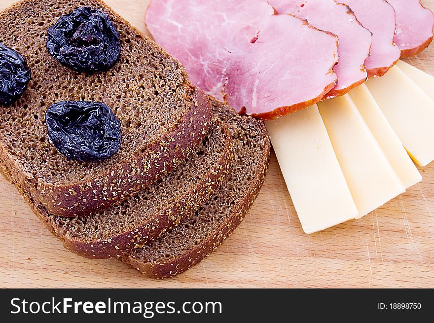 Sliced bread, cheese and ham on wooden board